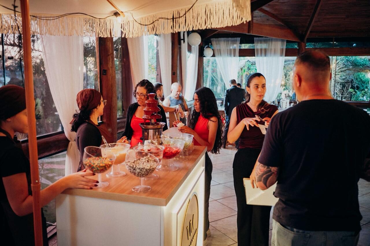 Estação de fondue com cascata de chocolate, atendentes e convidados