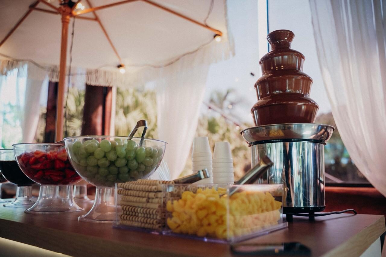 Estação de fondue montada ao ar livre com taças de frutas